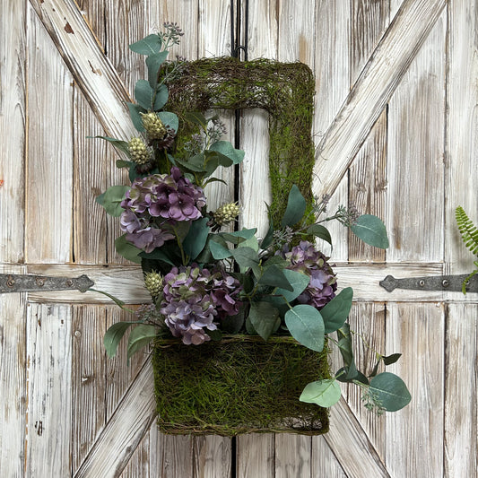 Rectangular green mossy basket, approximately 30" tall by 15'' wide. The basket features a floral arrangement with 3 realistic pale lavender hydrangeas with a variety of greenery.